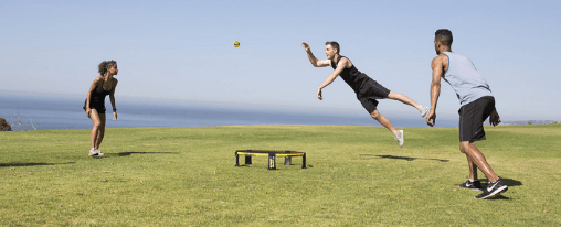  Zwei Teams spielen Spikeball als Freizeitspiel auf einer Wiese mit Netz und Ball