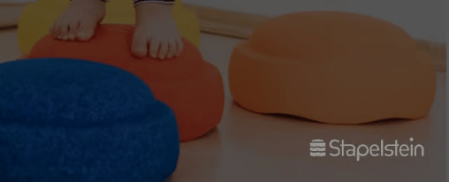 Kinder spielen mit Stapelsteinen in einer Kita und bauen Bewegungsparcours